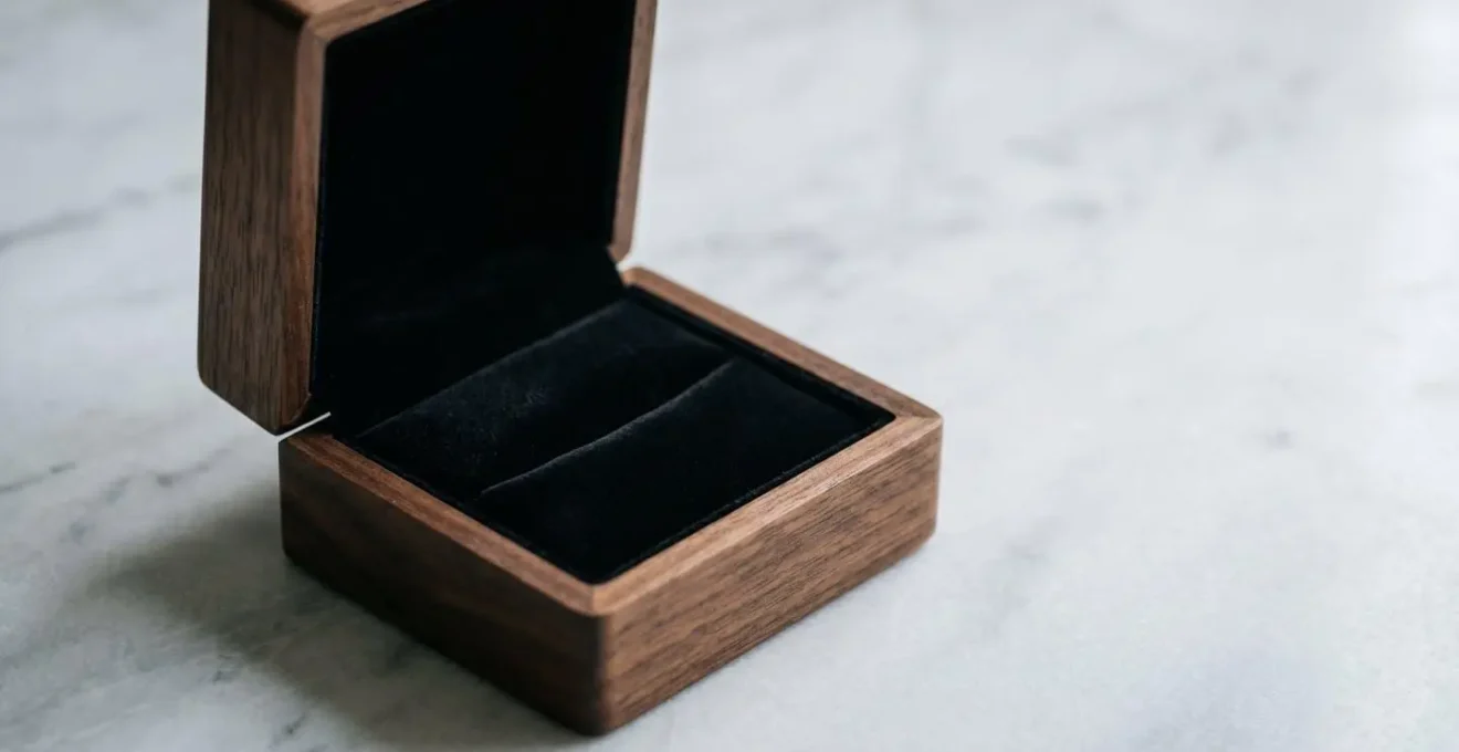 Écrin de luxe ouvert révélant un intérieur en velours sombre, posé sur une surface épurée avec une lumière douce