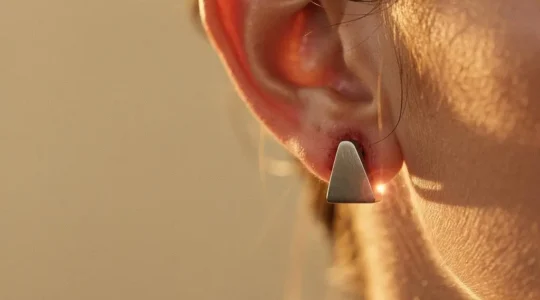 Gros plan artistique sur une oreille et un bijou minimaliste symbolisant une réaction allergène invisible